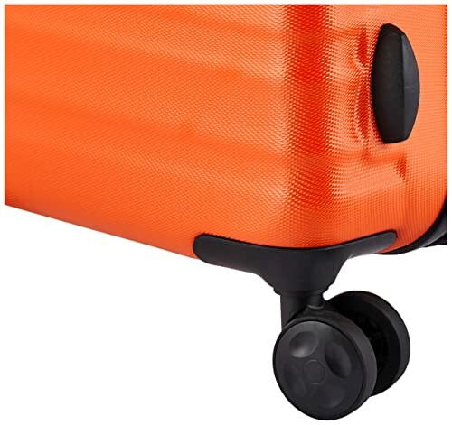 Close-up of an orange suitcase with a black wheel.