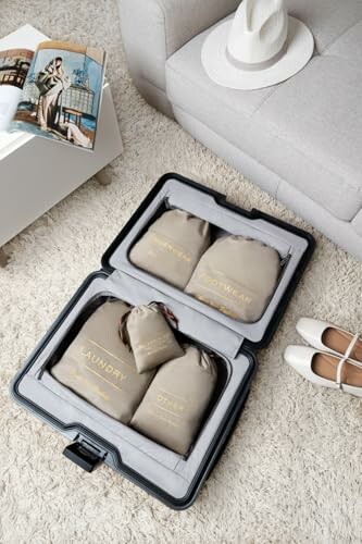 Open suitcase with labeled travel bags on carpet near sofa.