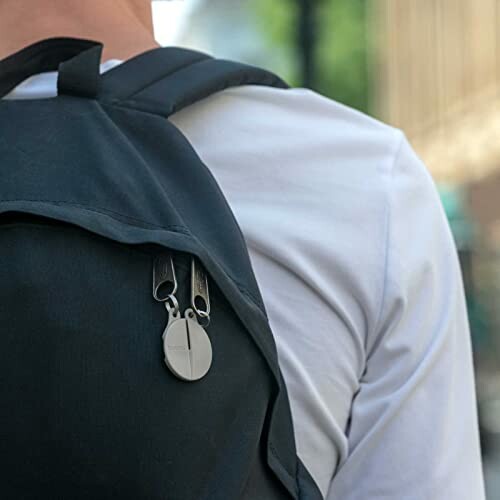 Person wearing a backpack with a round accessory attached.