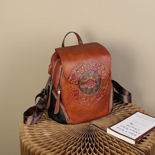 Vintage leather backpack with ornate design on a textured surface.